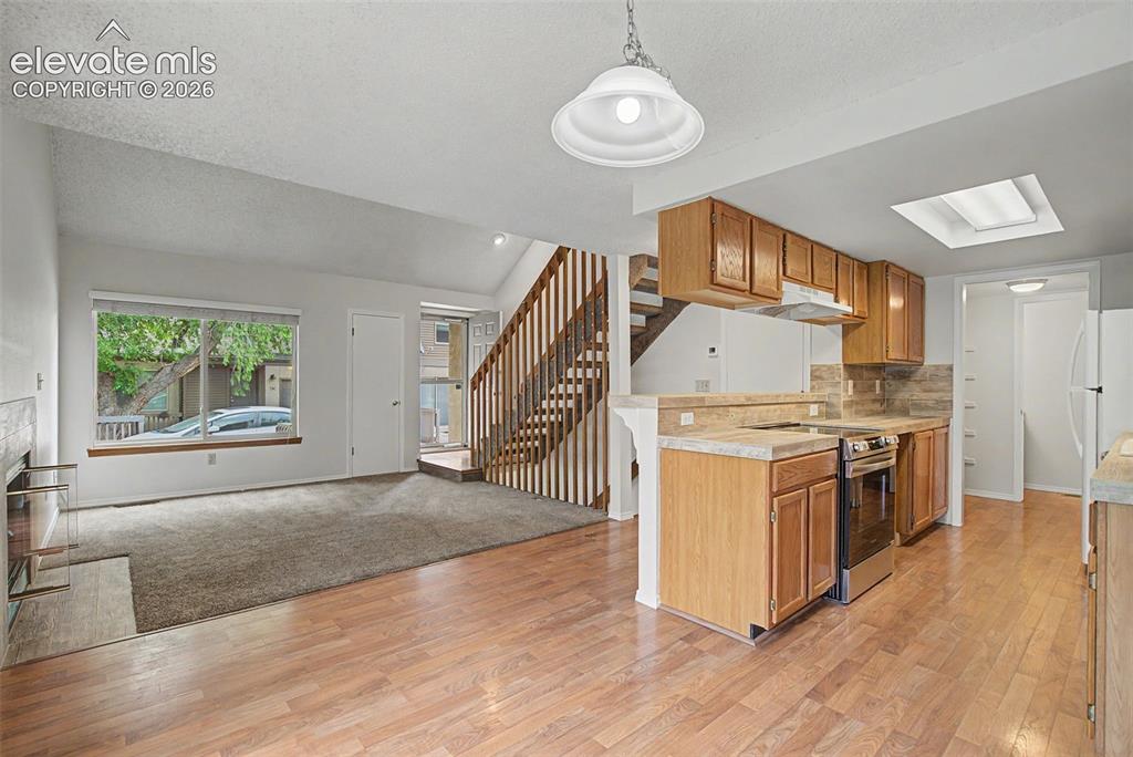 Image 11 of 30: Open-concept living space featuring wood-finish flooring, a carpeted lounge