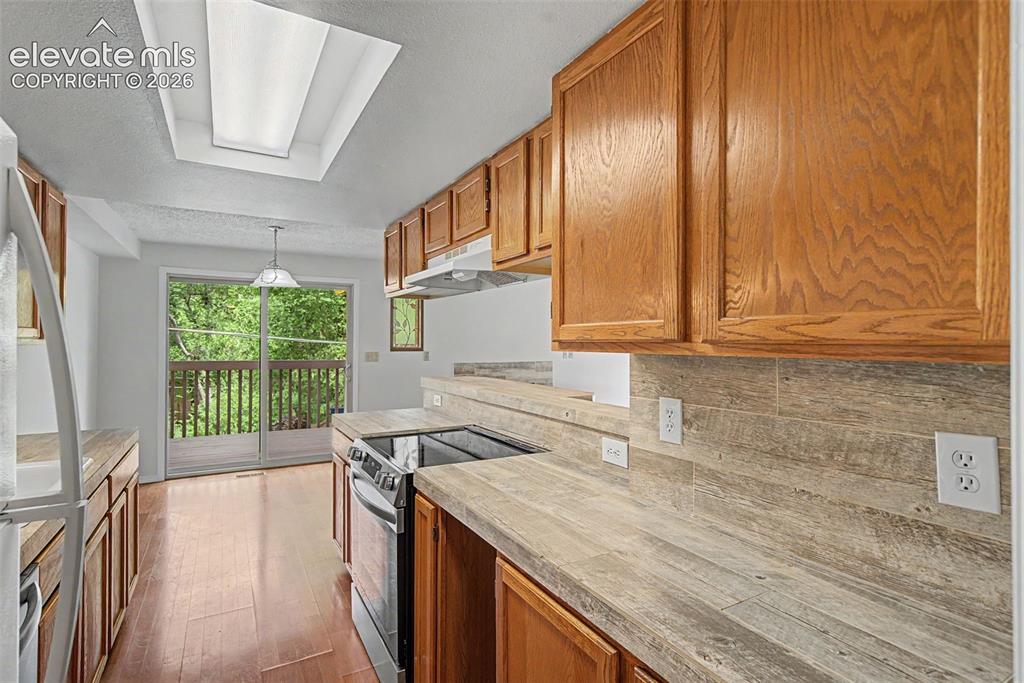 Image 12 of 30: Kitchen featuring wood-finish flooring, wood cabinetry, a built-in electric