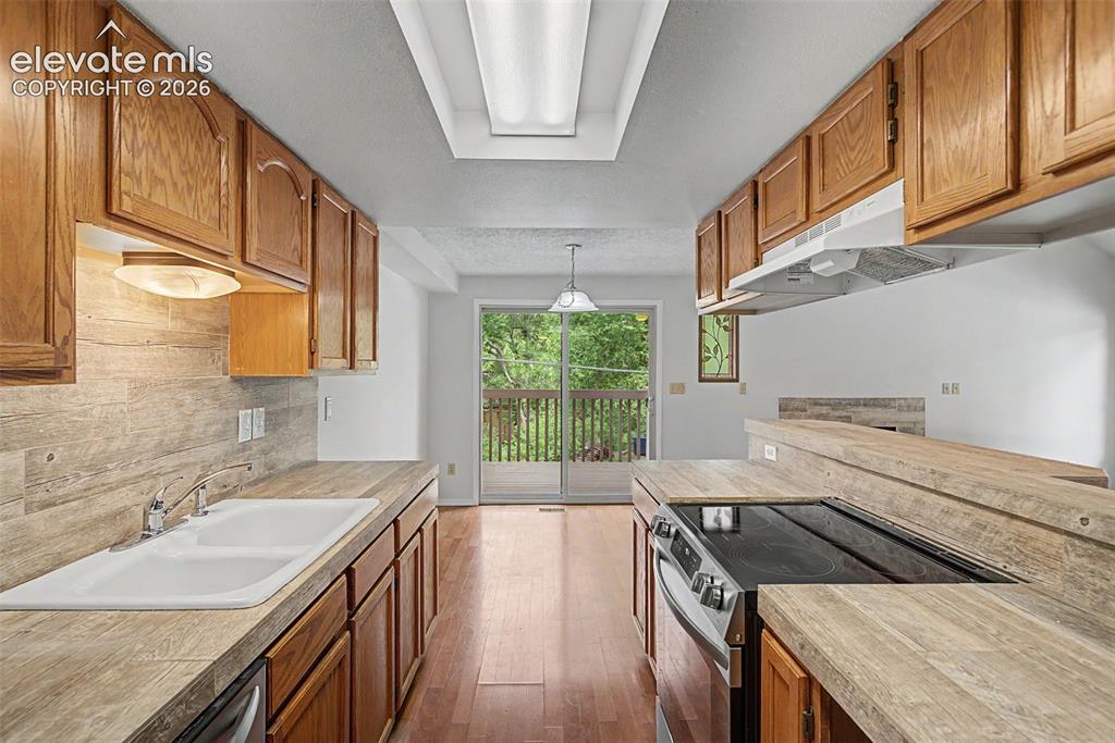 Image 13 of 30: Kitchen featuring wood cabinetry, wood-finish countertops, and a tile backs