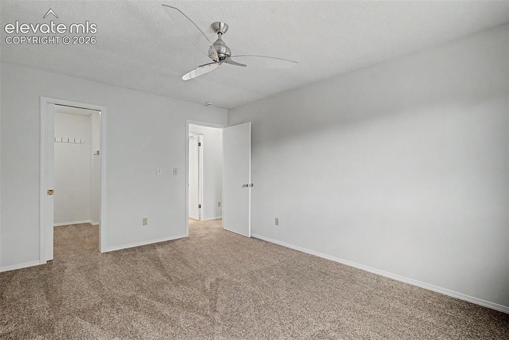 Image 22 of 30: Carpeted room with a modern ceiling fan, white walls, and white trim