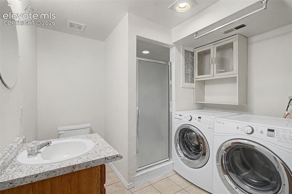 Image 28 of 30: Functional utility space featuring a shower enclosure, vanity with a speckl