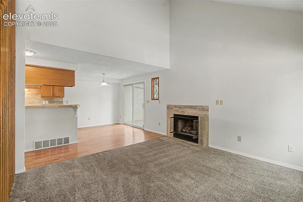 Image 5 of 30: Living area with vaulted ceilings, a fireplace featuring a stone-tile surro