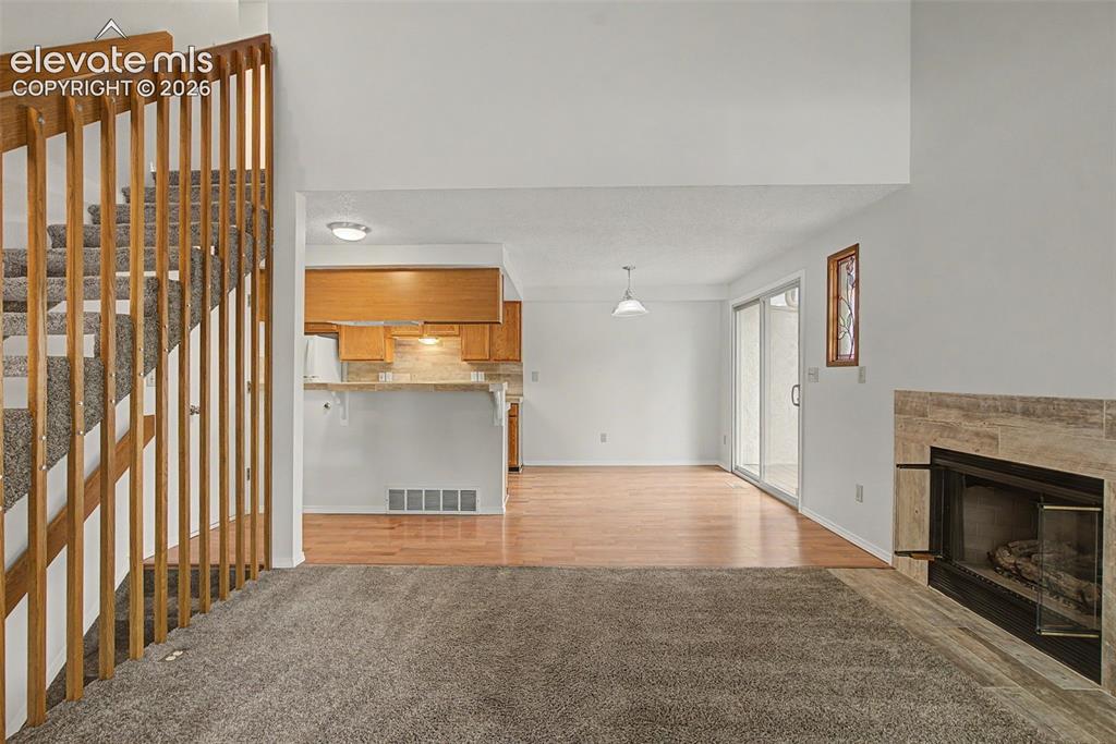 Image 6 of 30: Living space featuring a stone-clad fireplace and sliding glass door