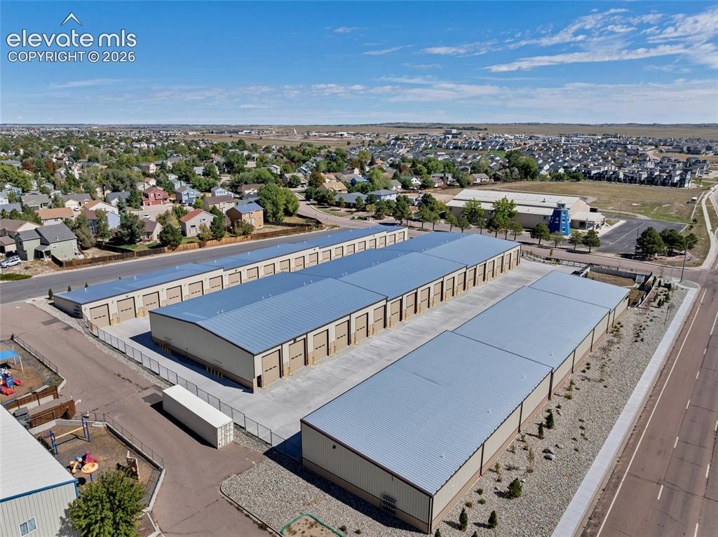 Image 11 of 20: Multiple storage buildings with metal roofs and roll-up doors, paved drivew