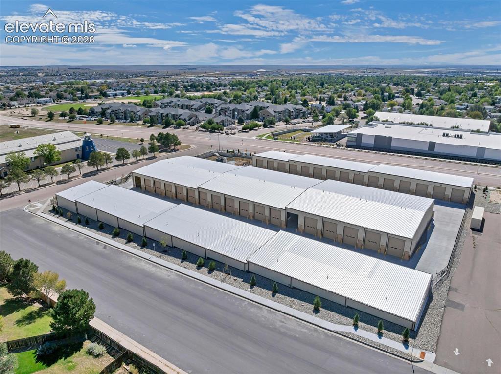 Image 16 of 20: Multiple storage buildings with metal roofs, individual roll-up doors, and