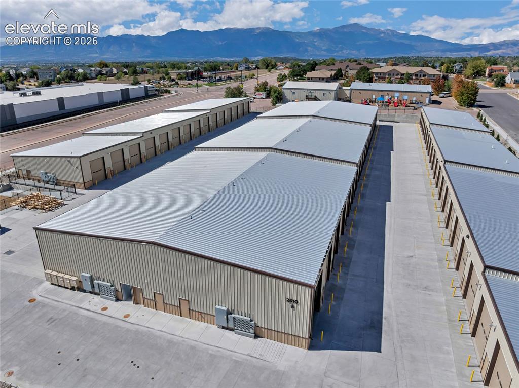 Image 19 of 20: Mountain backdrop, multiple storage buildings, light-colored metal roofing,
