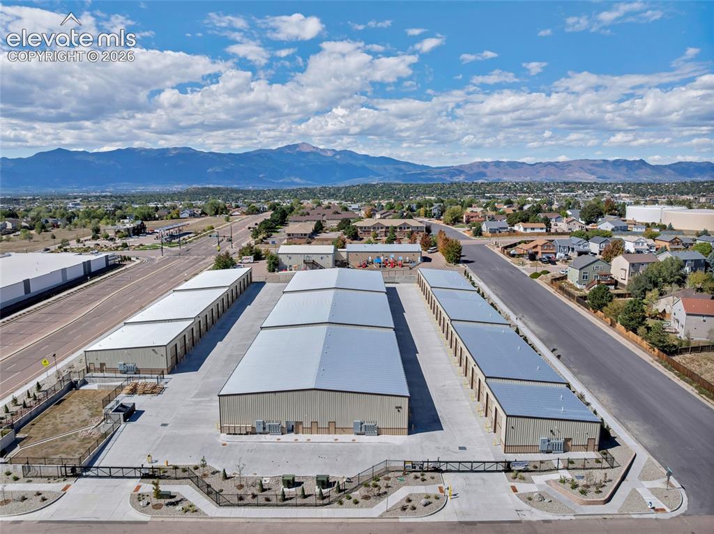 Image 20 of 20: Multiple storage buildings with metal roofs, paved access roads, and fenced