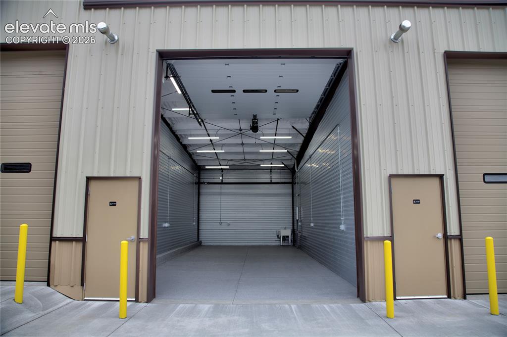 Image 7 of 20: Wide overhead door entrance, concrete flooring, corrugated metal walls, and