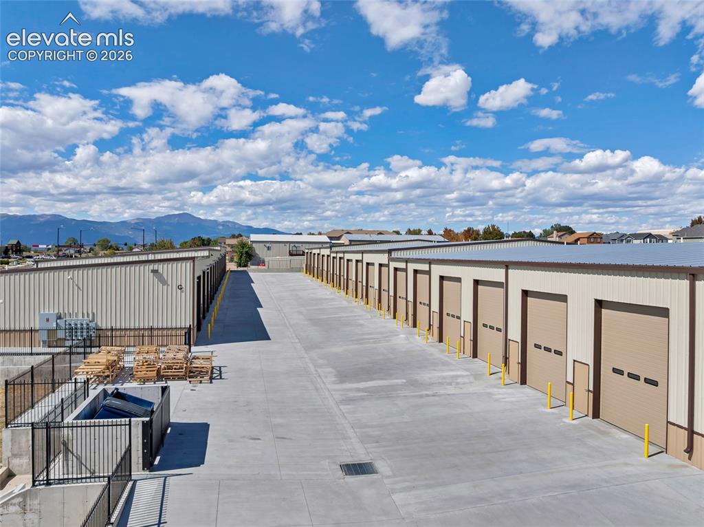 Image 9 of 20: Expansive concrete driveways with multiple storage units featuring roll-up 