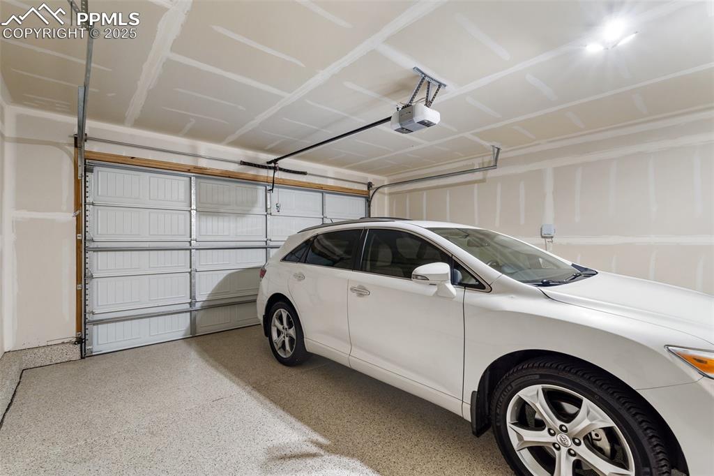Image 36 of 49: 2 car garage has finished drywall and epoxy floors