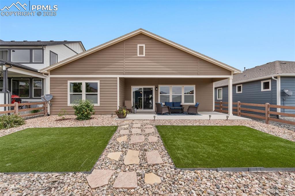 Image 37 of 49: Covered back patio and beautifully landscaped backyard