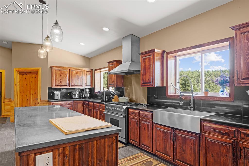 Image 13 of 40: Kitchen with decorative backsplash, dark countertops, high end range, a cen