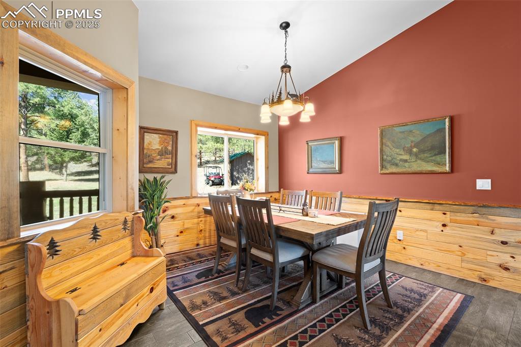 Image 18 of 40: Dining room featuring lofted ceiling, dark wood-style floors, and a chandel