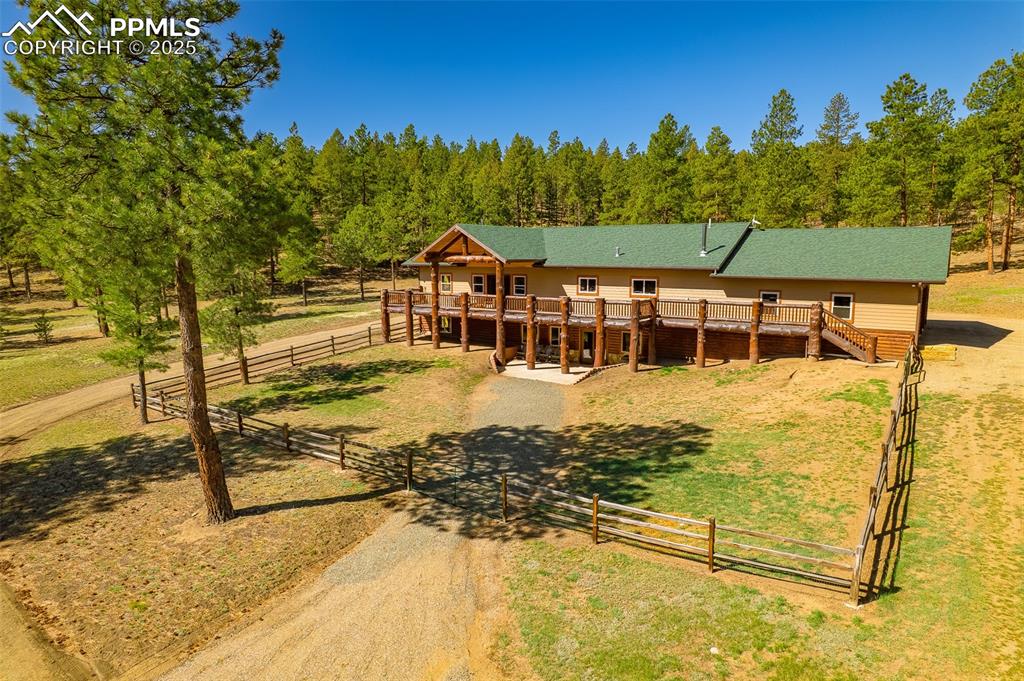 Image 2 of 40: View of front of property with stairs, a deck, a view of trees, and a rural
