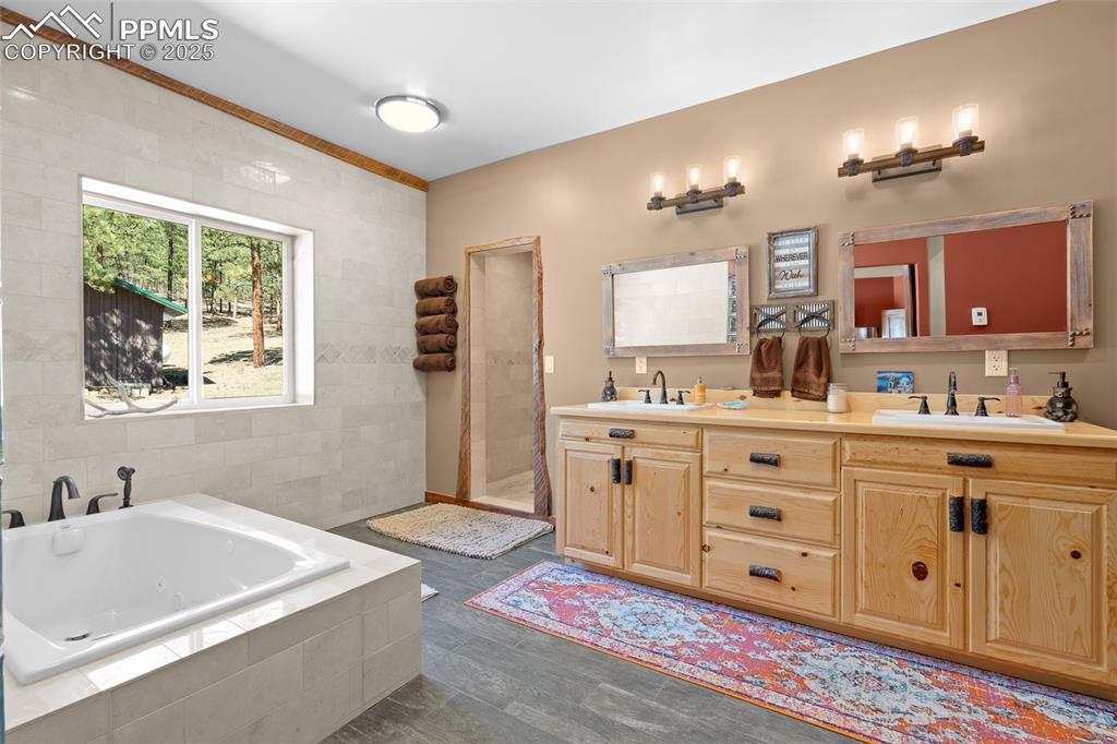 Image 22 of 40: Full bathroom featuring double vanity, a jetted tub, a stall shower, and ti