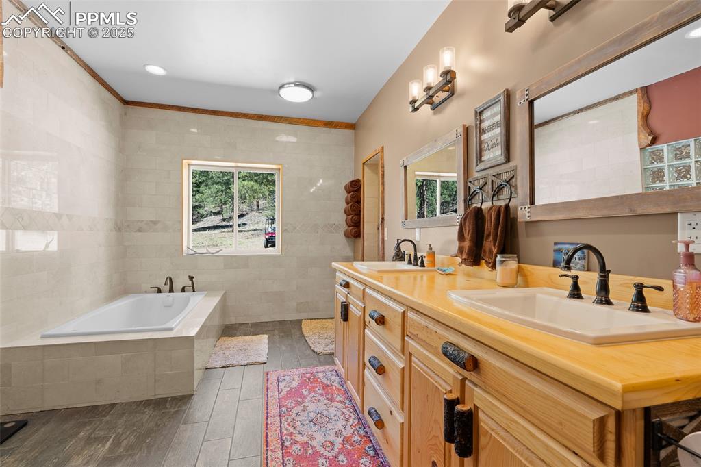 Image 23 of 40: Full bath featuring double vanity, a garden tub, wood finished floors, and