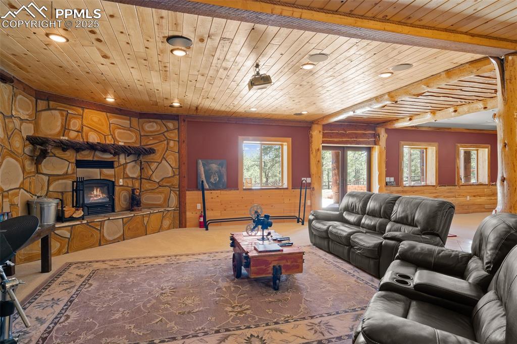 Image 28 of 40: Carpeted living area with recessed lighting, wood ceiling, and wooden walls