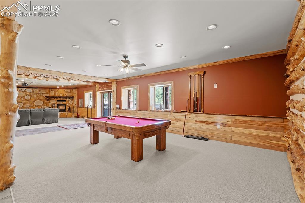 Image 33 of 40: Rec room featuring a fireplace, carpet flooring, wood walls, recessed light