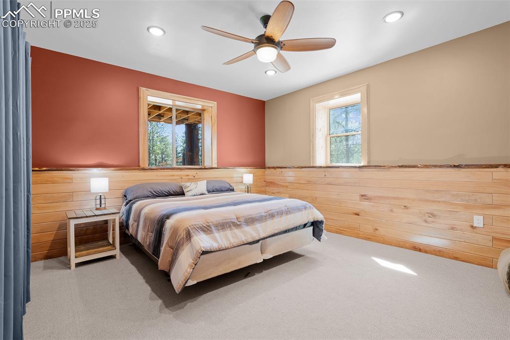Image 36 of 40: Bedroom featuring a wainscoted wall, carpet floors, wooden walls, multiple