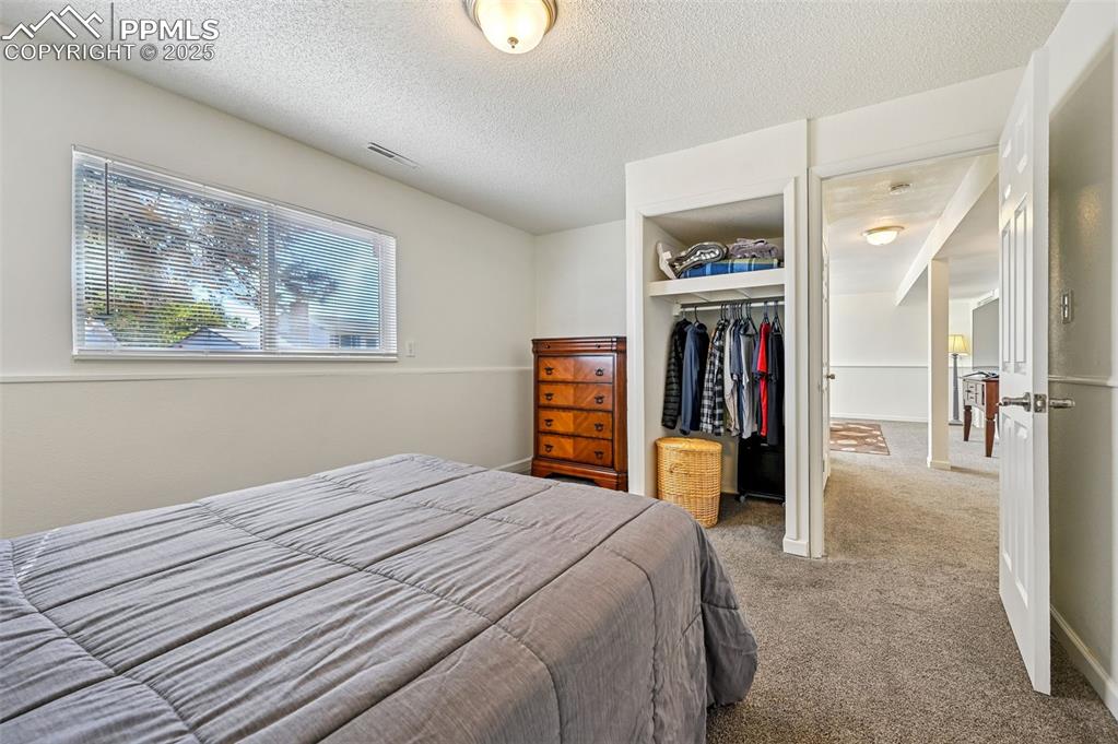 Image 22 of 27: Bedroom with carpet, a textured ceiling, and a spacious closet