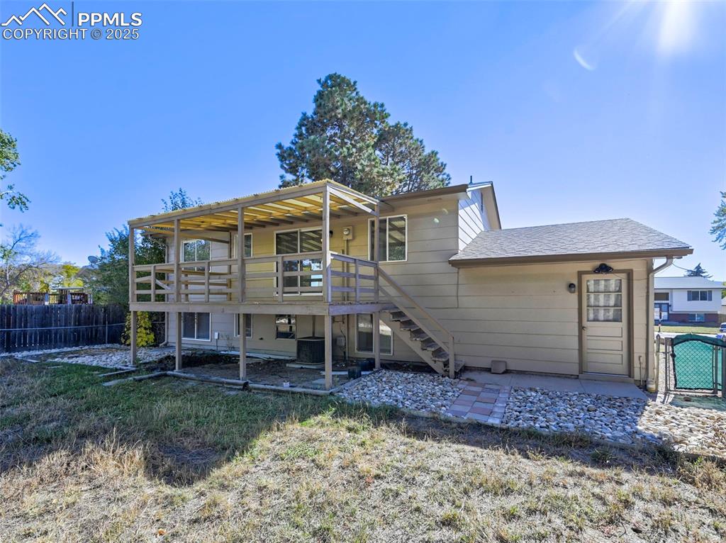 Image 6 of 27: Back of house featuring stairs, a wooden deck, a gate, and a shingled roof