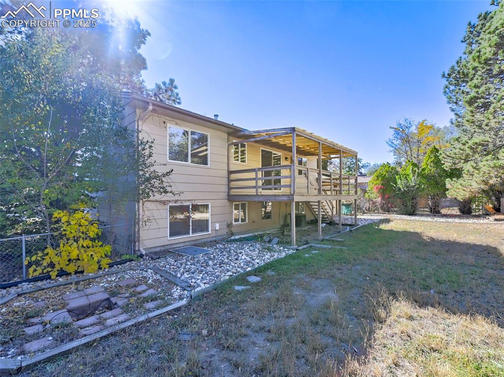 Image 7 of 27: Back of house with stairs, a wooden deck, and a yard