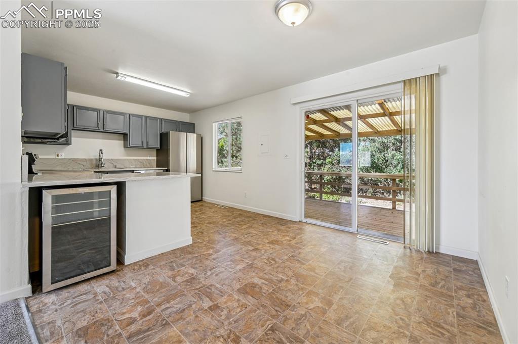 Image 8 of 27: Kitchen featuring wine cooler, gray cabinets, a peninsula, freestanding ref