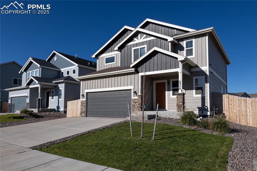 Image 2 of 32: View of front of home with board and batten siding, stone siding, concrete 