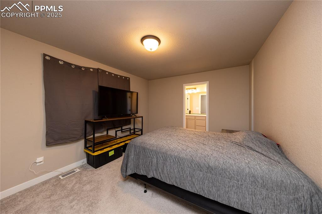 Image 22 of 32: Bedroom with light colored carpet and ensuite bathroom