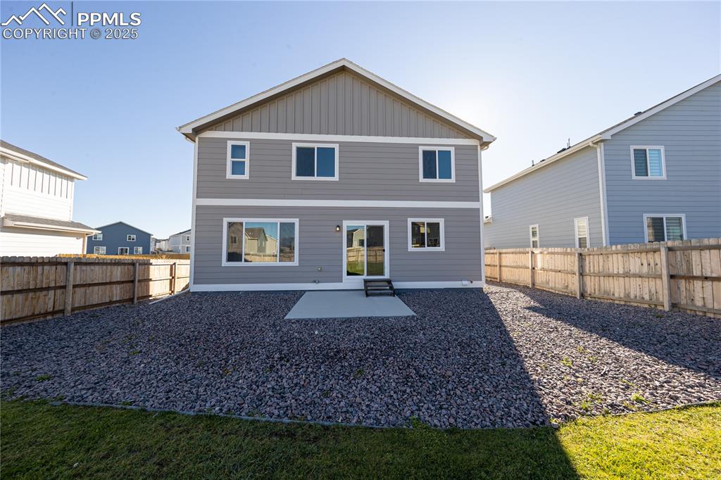 Image 28 of 32: Rear view of house with a patio, board and batten siding, and a fenced back