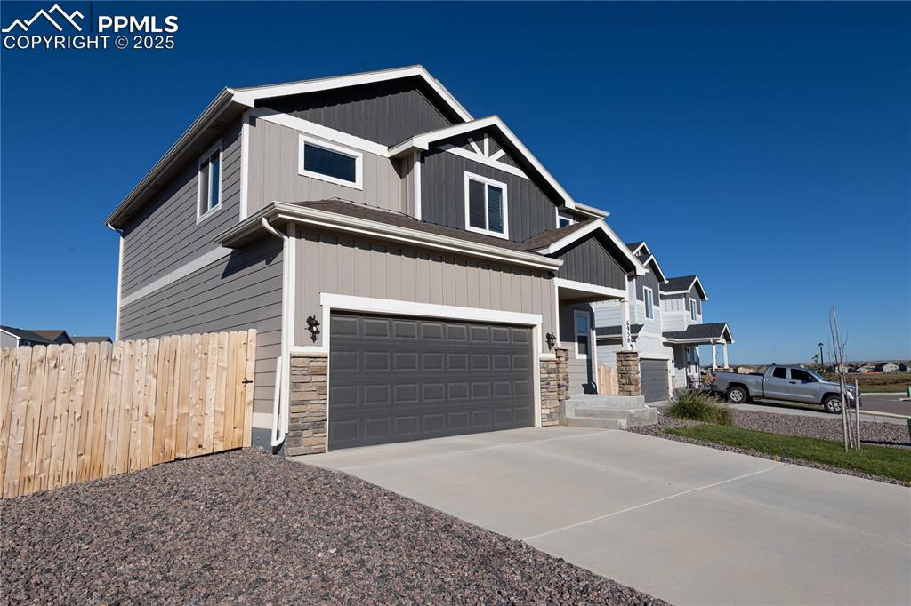 Image 3 of 32: Craftsman-style home with an attached garage, driveway, and stone siding