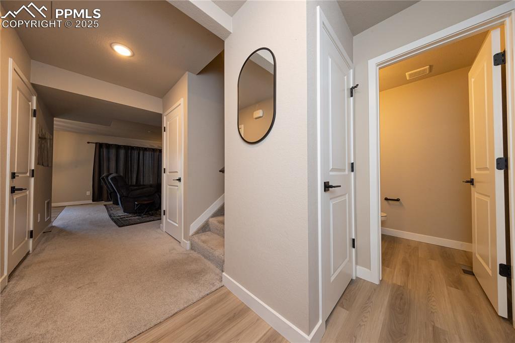 Image 5 of 32: Hall with light wood finished floors, stairway, and recessed lighting