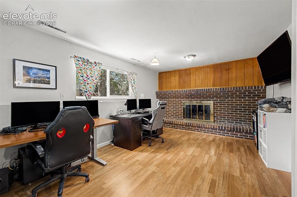 Image 19 of 44: This lower level family room features a stunning brick gas fireplace, garde