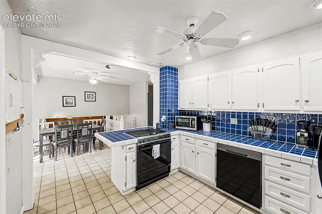 Image 9 of 44: Bright white kitchen with whimsical tile countertops, a brand new dishwashe