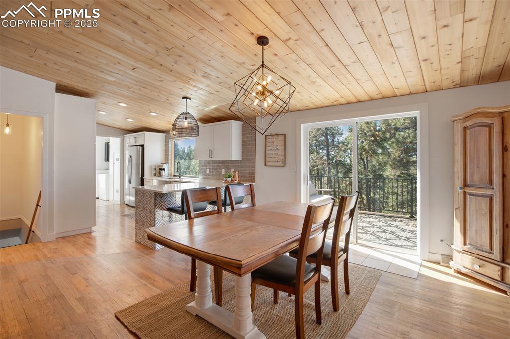Image 18 of 47: Dining area with wooden ceiling, light wood-style floors, a chandelier, and