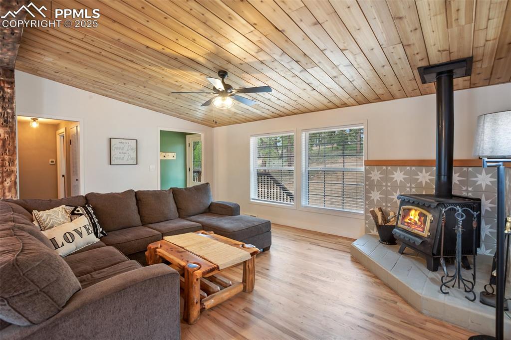 Image 2 of 47: Living area featuring a wood stove, vaulted ceiling, a ceiling fan, wooden 