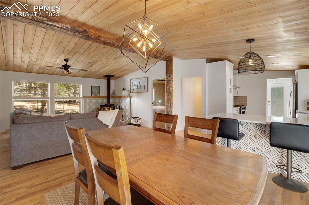 Image 20 of 47: Dining area featuring a wood stove, light wood-style flooring, wooden ceili