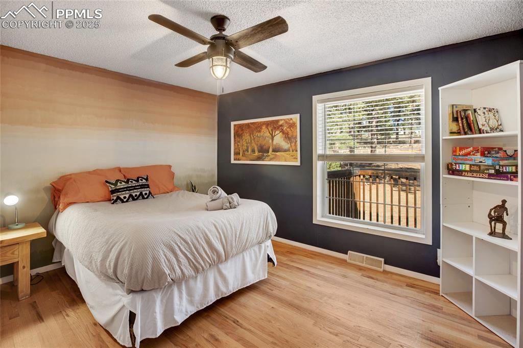 Image 22 of 47: Bedroom featuring wood finished floors, a textured ceiling, and a ceiling f