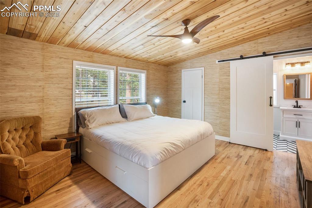 Image 23 of 47: Bedroom featuring a barn door, lofted ceiling, wooden ceiling, light wood f
