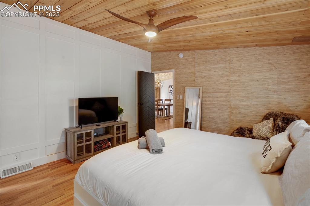 Image 25 of 47: Bedroom featuring wooden ceiling, a decorative wall, light wood finished fl