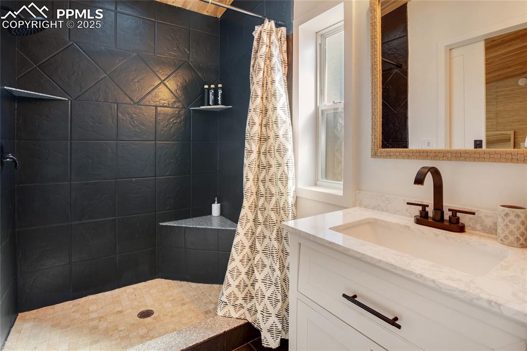 Image 26 of 47: Full bathroom featuring tiled shower and vanity