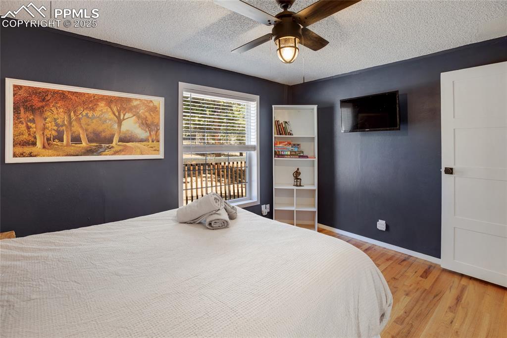 Image 28 of 47: Bedroom featuring wood finished floors, a textured ceiling, and a ceiling f