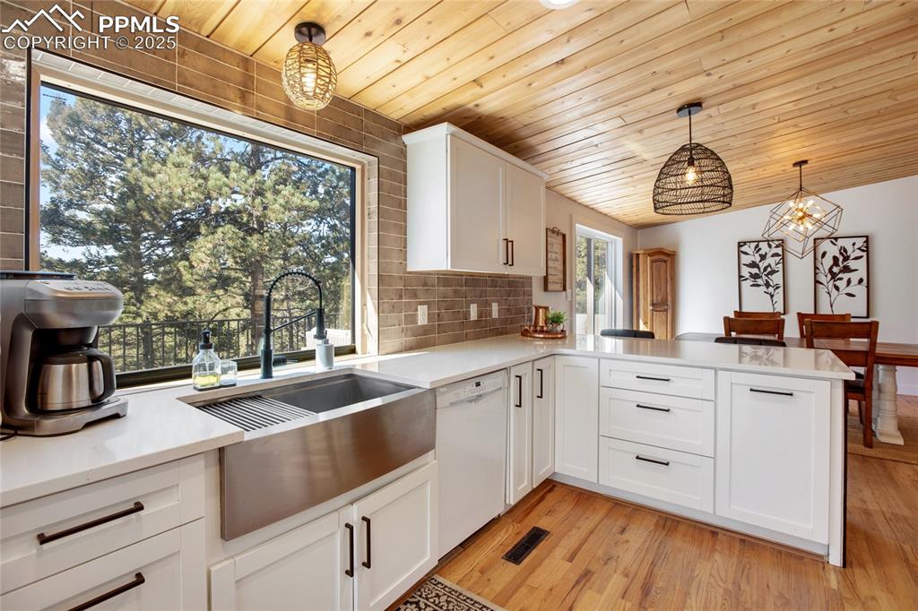 Image 3 of 47: Kitchen featuring white dishwasher, wood ceiling, light countertops, a peni