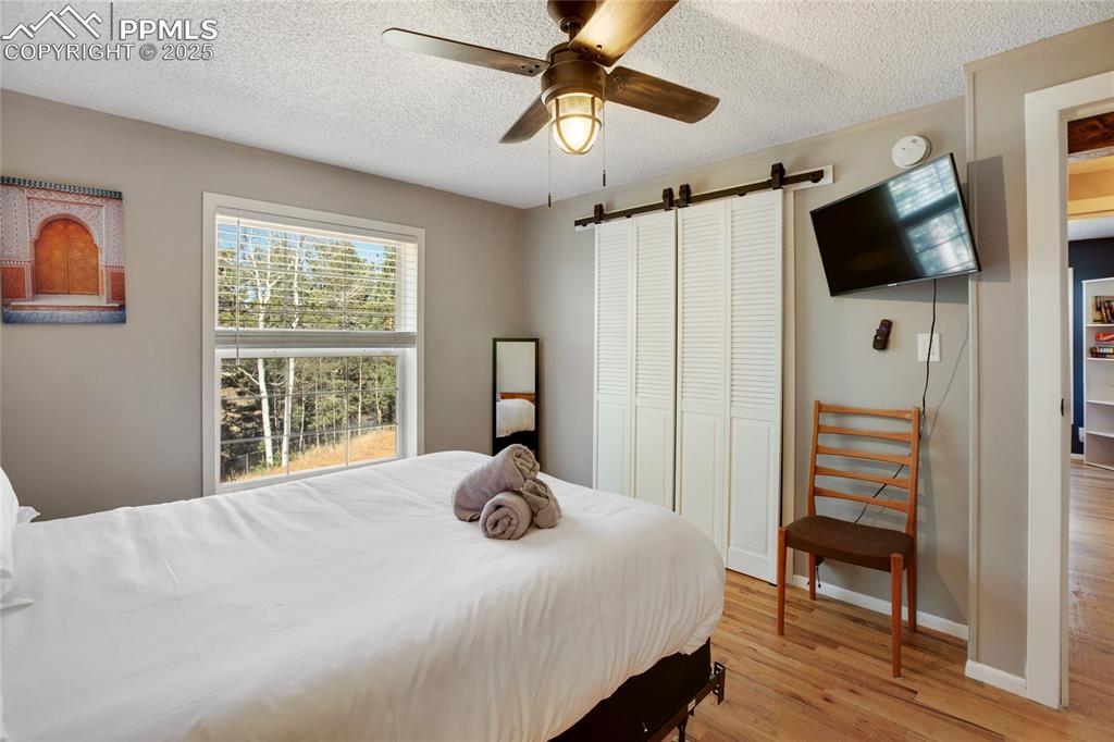 Image 30 of 47: Bedroom featuring a barn door, a textured ceiling, light wood finished floo