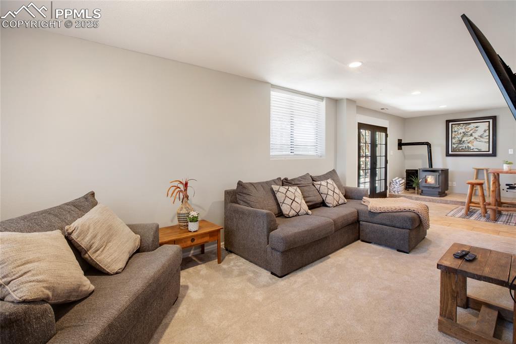 Image 33 of 47: Living room featuring a wood stove, light carpet, and recessed lighting