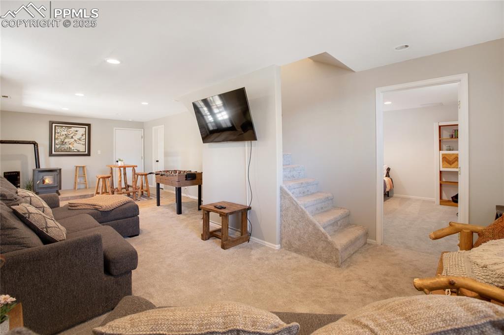 Image 35 of 47: Living room with carpet flooring, a wood stove, and recessed lighting