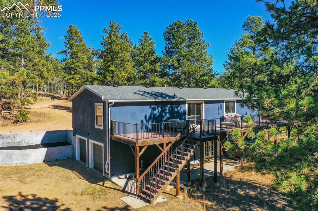 Image 43 of 47: Rear view of house with a wooden deck, an attached garage, stairway, dirt d