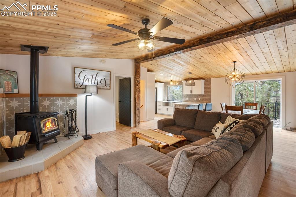 Image 5 of 47: Living room with a wood stove, plenty of natural light, wooden ceiling, a c