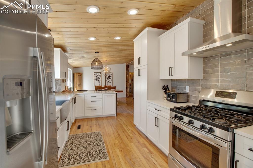 Image 8 of 47: Kitchen with stainless steel appliances, wall chimney exhaust hood, a penin