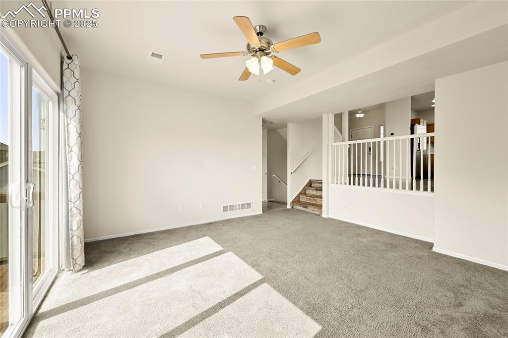Image 11 of 28: Unfurnished room with stairway, carpet floors, and ceiling fan